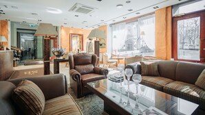 Eine geräumige Lobby mit Ledersofas, einem Glastisch und einem großen Fenster mit Blick auf die Stadt.