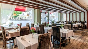 Ein Restaurant mit Holzbalkendecken, weißen Tischdecken und Samtsesseln.
