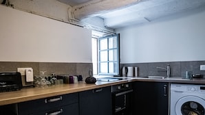 Una cocina moderna con lavadora integrada, cafetera y ventana que proporciona luz natural.