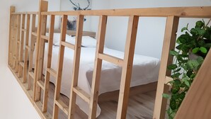 Une pièce avec une cloison en bois, un lit avec une literie blanche et une œuvre d’art accrochée au mur.