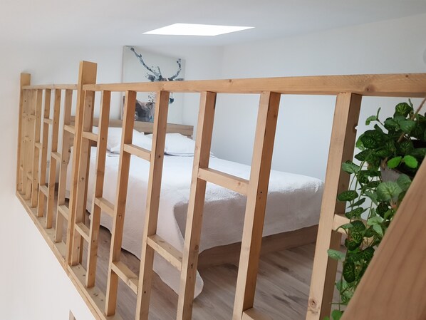 Une chambre à coucher avec un cadre de lit en bois, un matelas blanc et un tableau accroché au mur.