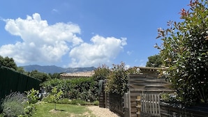 Un jardin bien entretenu, avec un ciel dégagé, une clôture en bois et une vue sur des montagnes lointaines.