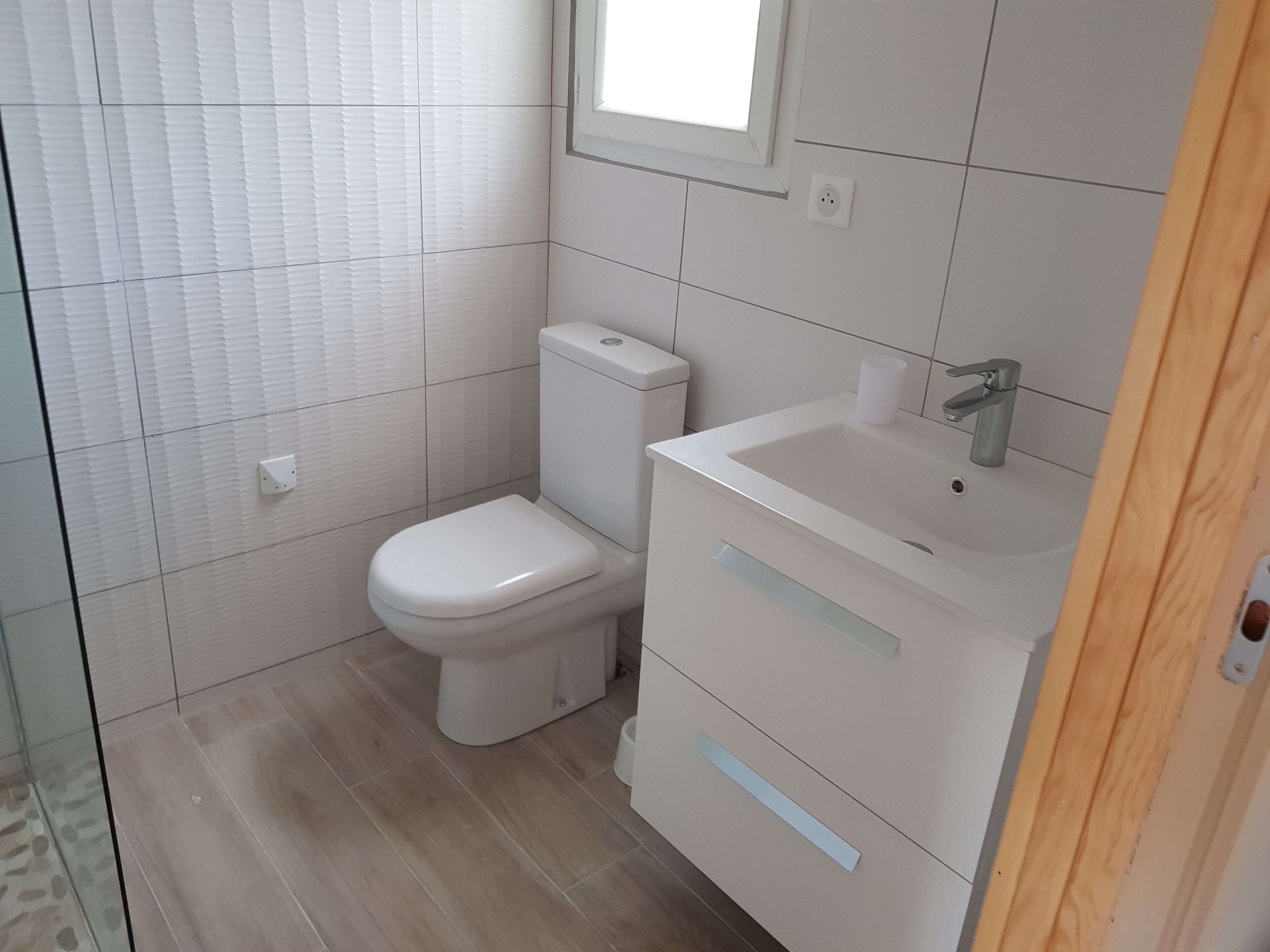 Et badeværelse med toilet, håndvask og skab.