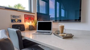 A modern workspace with a laptop, a coffee cup, and a tray of cookies on a white desk. - Papillon, a modern Southwold flat with balcony (Southwold)