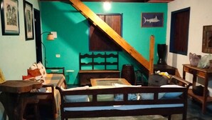 Una habitación con cama, escritorio, silla, escalera de madera y ventilador de techo.