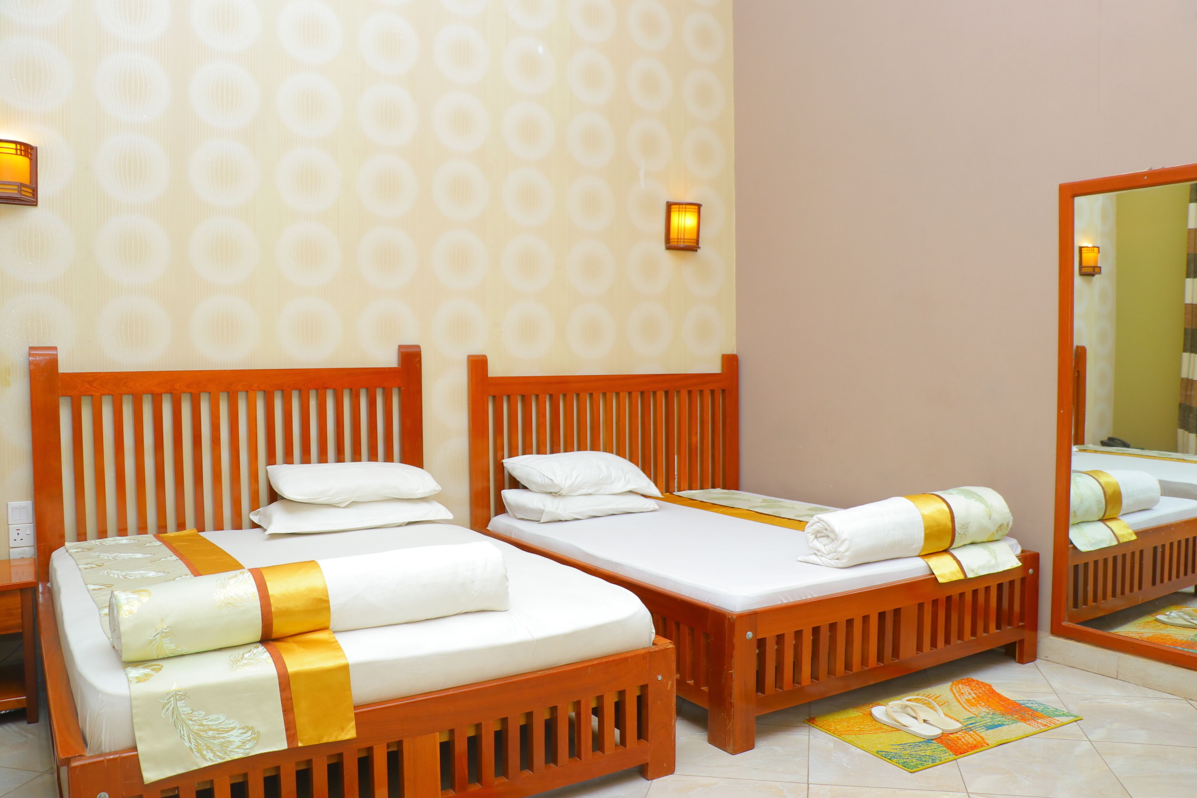 Una habitación de hotel con dos camas de madera, ropa de cama blanca y un espejo grande.