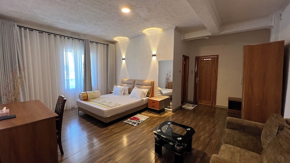 A hotel room with a large bed, bedside tables, a desk, and a wardrobe. - Lush Garden Hotel (Arusha)