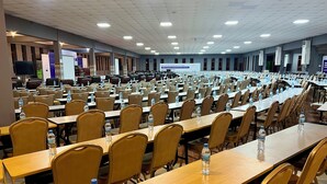 A large conference room with rows of tables and chairs, equipped with water bottles. - Lush Garden Hotel (Arusha)