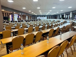 A large conference room with rows of tables and chairs, equipped with water bottles. - Lush Garden Hotel (Arusha)