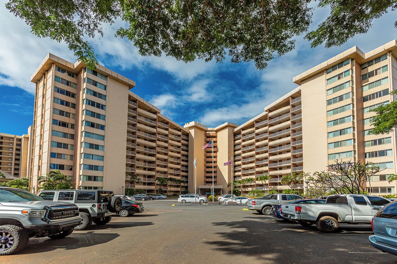 A multi-story hotel with a parking lot in front.