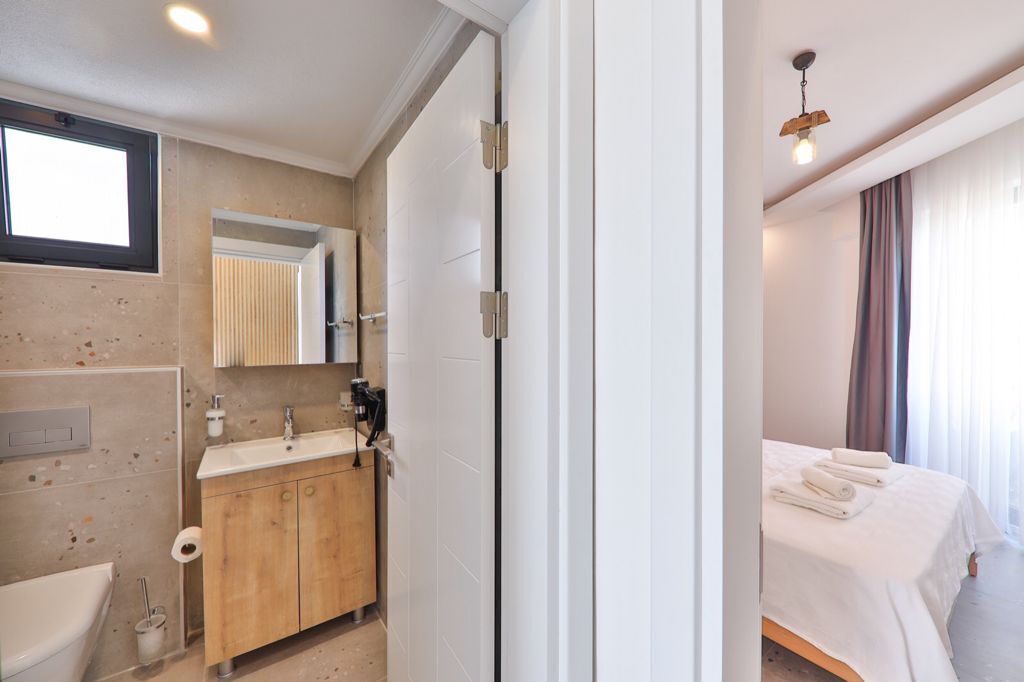 A modern bathroom with a sink, mirror, and toilet.