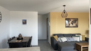 Un salon moderne avec un canapé d’angle gris, une table basse en bois et un coin repas comprenant une table et des chaises.