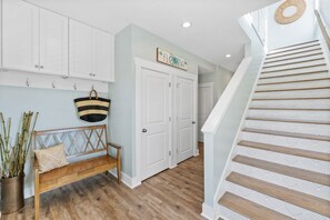 A hallway with a wooden bench, a hanging basket, and a staircase with patterned steps.