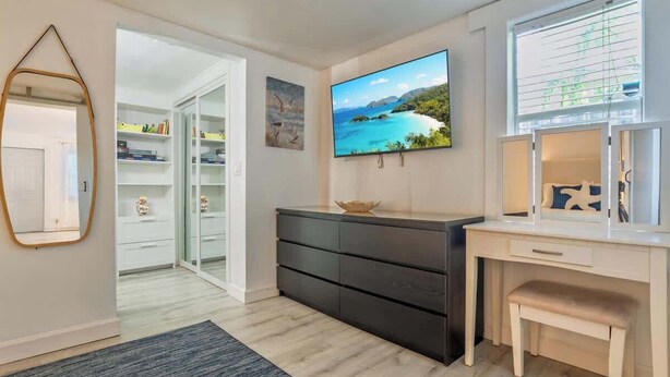 Een kamer met een bureau, een televisie, een spiegel en een kledingkast.