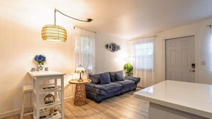 Een moderne woonkamer met een bank, een witte tafel, een lamp en een hanglamp.
