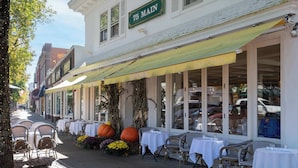 Een restaurant met terras, tafels met witte tafellakens, en een grote pompoen decoratie.