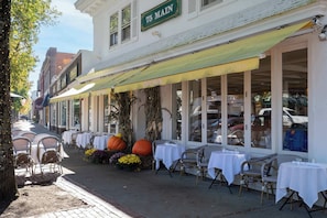 Un restaurant avec une terrasse, des tables recouvertes de nappes blanches et une grande décoration en forme de citrouille.