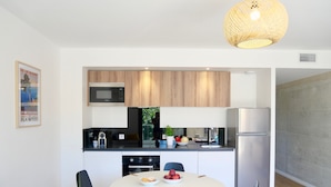 Une cuisine moderne avec des meubles en bois, un four à micro-ondes encastré et un réfrigérateur en acier inoxydable.