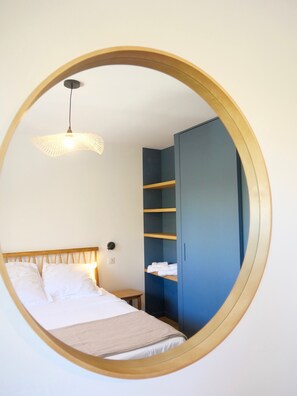 A bedroom with a bed, a bedside table, a wardrobe, and a hanging light fixture.