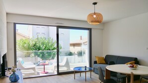 Un salon moderne avec balcon, un coin repas et un canapé.