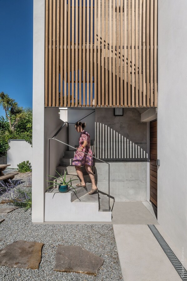 A modern building with a wooden slatted entrance, a concrete staircase, and a potted plant.