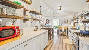 A spacious kitchen with white cabinets, a red vintage microwave, and various kitchen appliances. - Lakeview retreat with beach access. Stylish home just steps from Deep Run Beach. (Canandaigua)