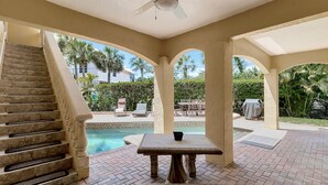 A covered outdoor area with a pool, a table, and a staircase. - "Pelican Nest"Private Beach & Bay access & Pool 4bedroom 3bath (Englewood)