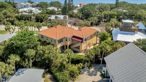 A two-story house with a red-tiled roof, surrounded by lush greenery and a view of a large body of water. - "Pelican Nest"Private Beach & Bay access & Pool 4bedroom 3bath (Englewood)