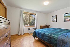 A bedroom with a bed, a wooden dresser, a desk, and a chair. There is a window with a view of trees and a door. - Breathtaking views on the Bay! Waterfrontage! (Sturgeon Bay)
