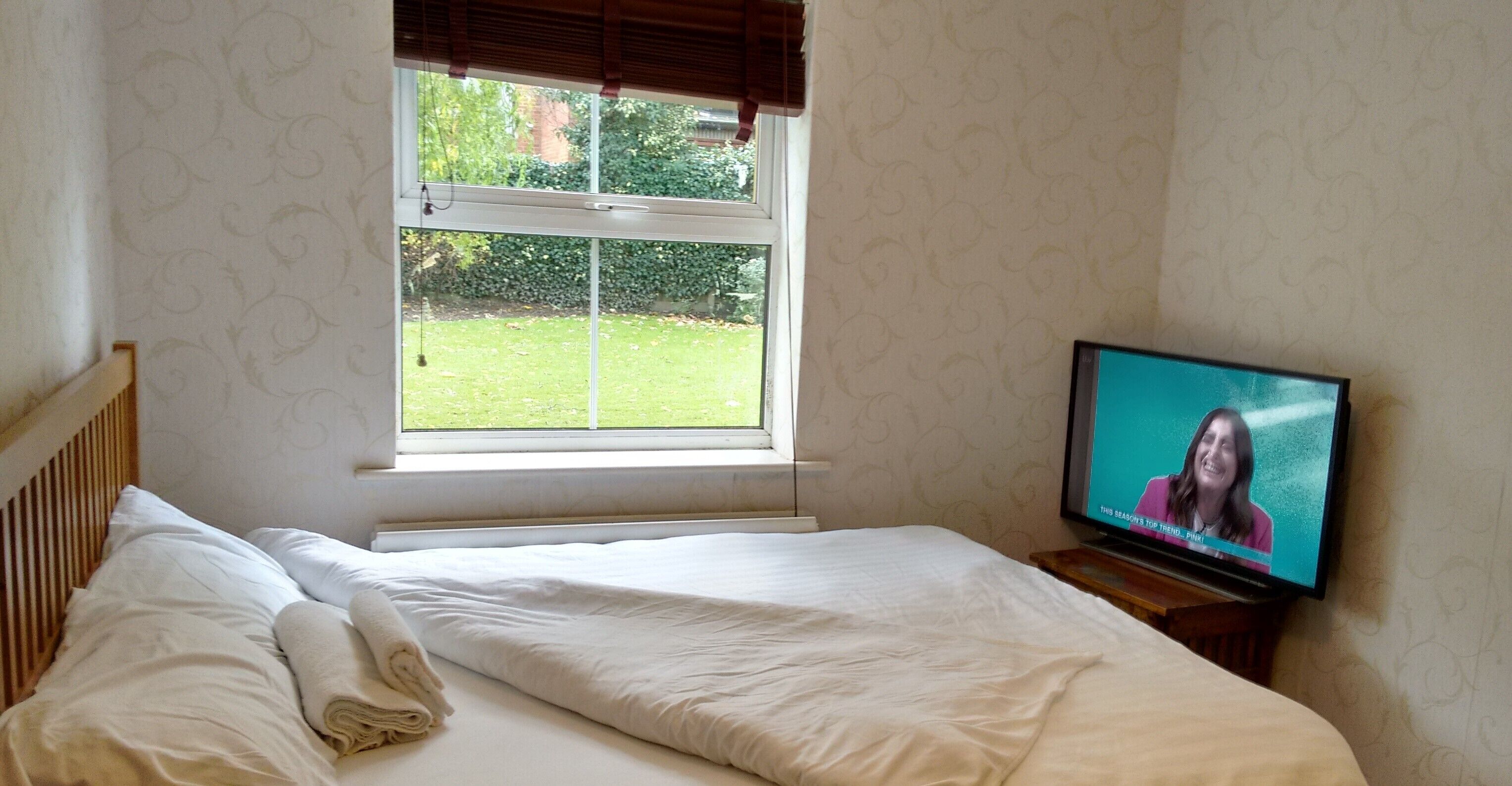 A bedroom with a bed, a window, and a television.