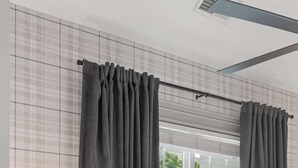 Een slaapkamer met een bed, een nachtkastje met een lamp en gordijnen.