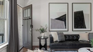 Een moderne woonkamer met een donkere leren bank, een ronde salontafel en een groot raam met gordijnen.