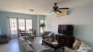 Un salon comprenant un canapé, des fauteuils, une table basse, un téléviseur et un ventilateur de plafond.