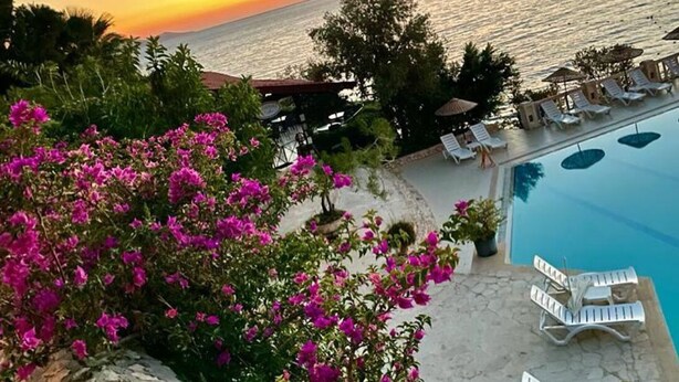 A poolside view with lounge chairs and a view of the sea at sunset. - Villa for rent in Club Patara holiday village (Kaş)