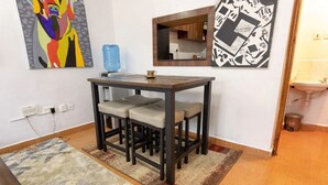 A small dining area with a table and four chairs, a blue water dispenser, and two artworks on the walls. - Cozy Family-sized 2 Bedroom Apartment with stable Wi-fi & conducive work station (Ruiru)