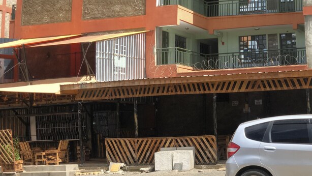 A multi-story building with balconies and a covered area with chairs and tables. - Cozy Family-sized 2 Bedroom Apartment with stable Wi-fi & conducive work station (Ruiru)
