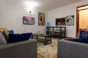A living room with a TV, a painting, and a small table.