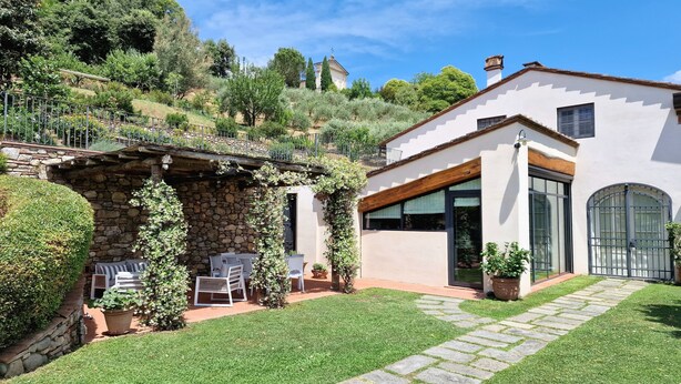A modern house with a stone wall and a patio area with outdoor furniture. - Old restored lemon house near the center (Lucca)