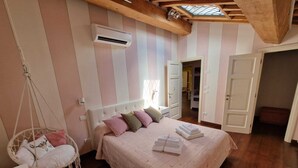 A bedroom with a bed, hanging chair, and an air conditioning unit. - Old restored lemon house near the center (Lucca)