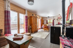 A cozy cabin interior with a dining area, kitchen, and a large window with curtains.