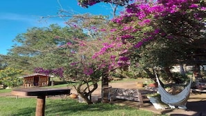 A hammock, a wooden bench, and a small wooden structure in a garden with blooming pink flowers. - TINY HOUSES TO RELAX IN THE COUNTRYSIDE ITAI AVARÉ HOLAMBRA II REP JURUMIRIM (Itaí)
