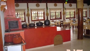 A restaurant with a central red counter, multiple black pots on display, and a traditional stove. - TINY HOUSES TO RELAX IN THE COUNTRYSIDE ITAI AVARÉ HOLAMBRA II REP JURUMIRIM (Itaí)