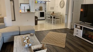A modern living room with a sofa, coffee table, TV stand, and fireplace. - Literally: 15 steps to the Heated Pool/Ground Floor Condo/King Bed/Free Parking (Clearwater)