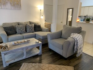 A living room with a grey sectional sofa, a wooden coffee table, and a grey armchair.