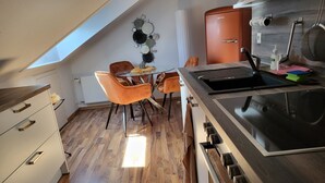 Een moderne keuken met dakraam, houten vloer en een eethoek met oranje stoelen.