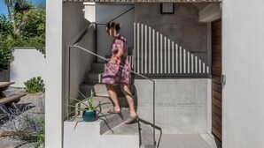 A modern building with a wooden slatted entrance, a concrete staircase, and a potted plant.
