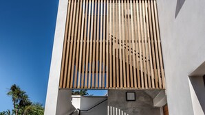 A modern building with a concrete staircase, wooden slats on the upper level, and a potted plant on the lower level.