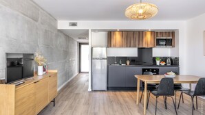 A modern kitchen with a dining area, featuring a wooden dining table, black chairs, and a built-in oven.