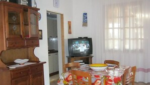 A dining area with a wooden cabinet, a television, and a table with chairs. - Holidays and relaxation 5 minutes from San Vito Lo Capo (custonaci)
