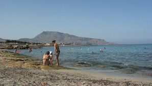 A beach with people swimming and standing in the water, a mountain in the background, and a rocky shoreline. - Holidays and relaxation 5 minutes from San Vito Lo Capo (custonaci)